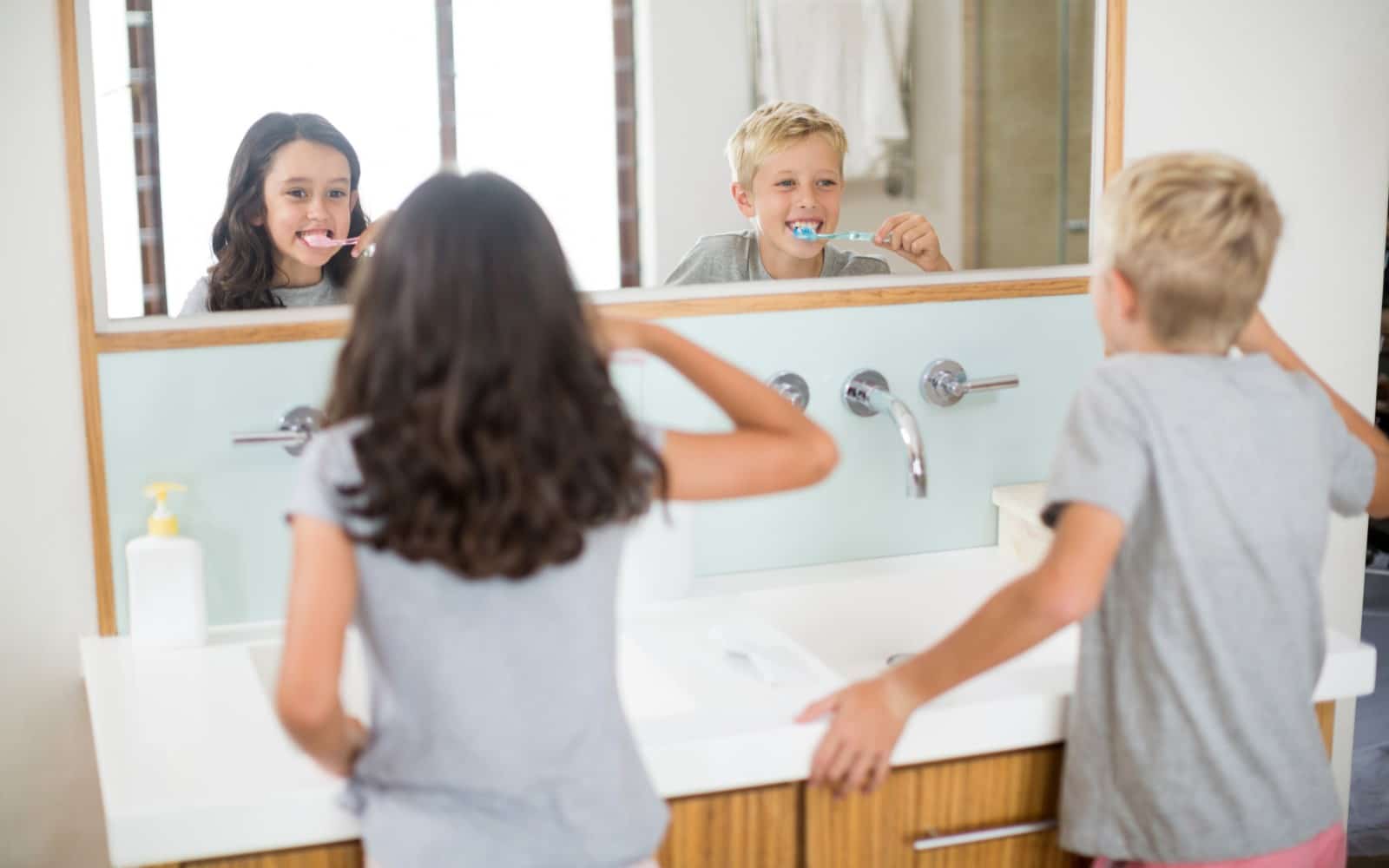 getting your child to brush and floss siblings brushing their teeth in the mirror